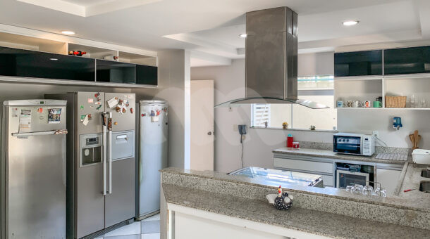 Imagem lateral da cozinha com vista dos móveis do imóvel à venda em condomínio de mansões.