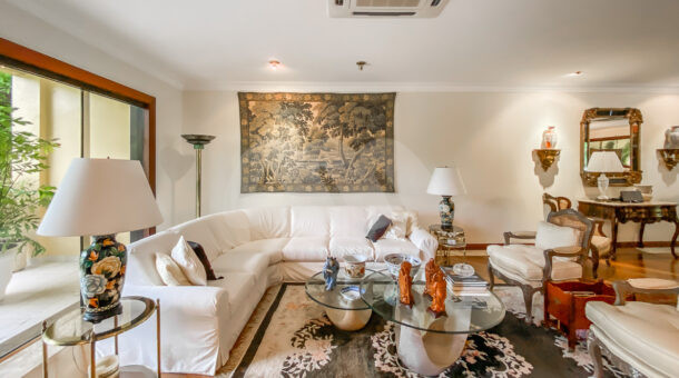 Imagem de sala de estar com sofá branco de canto e mesa de centro em casa a venda na barra