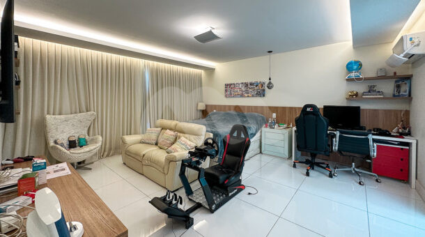 Imagem de quarto com cama de casal, sofá e cadeiras gamers em casa triplex a venda na Barra da Tijuca