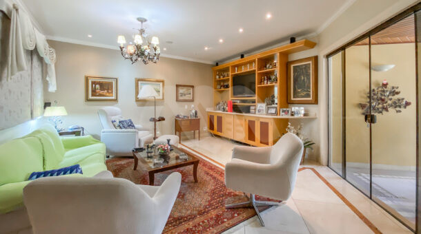 Imagem da sala com tv da casa brezinski semi-mobiliada à venda na Barra da Tijuca