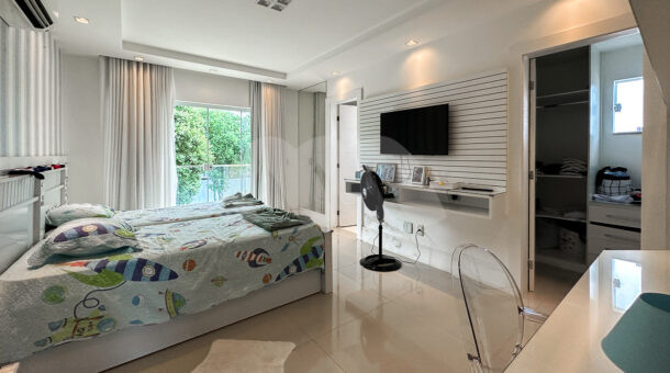 Imagem de suite com cama de solteiro, escrivaninha e painel de tv