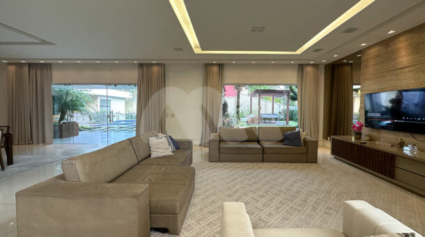 Imagem de ampla sala de estar com sofá e poltrona e rack com painel de tv da casa triplex à venda