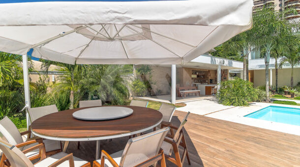 Imagem da área externa mesa e guarda-sol da casa duplex com Jardim de Inverno á venda na Barra da Tijuca