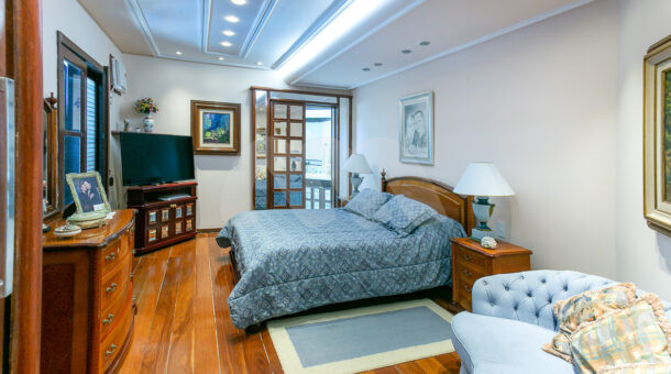 Imagem lateral da cama da suite da mansão moderna à venda na Muller Imóveis RJ.