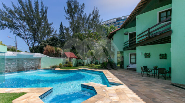 Imagem frontal da piscina da casa à venda em luxoso condomínio de mansões.
