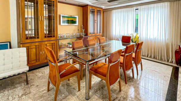 Imagem de sala de jantar com cristaleiras em madeira e vidro e mesa de jantar em vidro da casa duplex a venda na Muller Imoveis