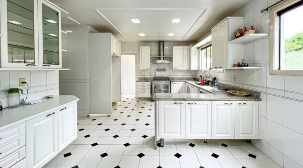 Imagem de ampla cozinha branca com peninsula e armarios planejados na casa duplex a venda na Barra da Tijuca
