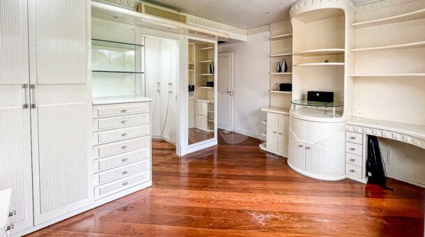 Imagem de amplo qurto com armarios planejados e acesso a closet da casa a venda na Barra