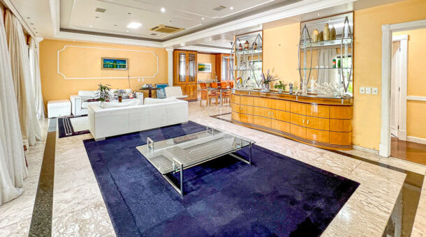 Imagem de ampla sala de estar com tapete e sofás e bar em madeira de casa duplex a venda