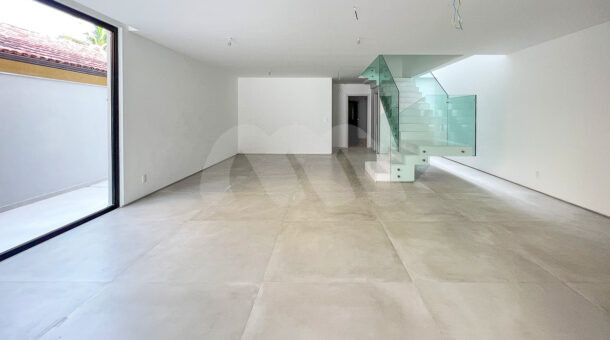 Imagem da ampla sala com escada com proteção de vidro da casa à venda em condomínio de alto padrão.
