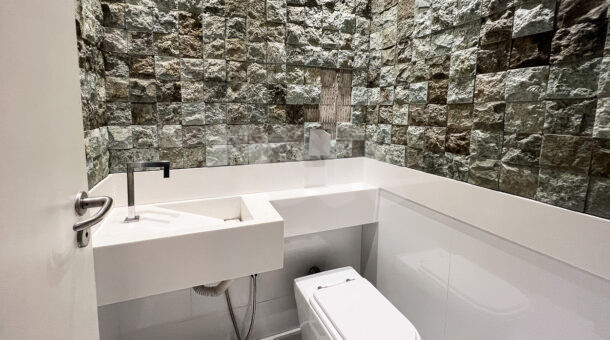 Imagem frontal do lavabo com paredes detalhadas em cinza do imóvel à venda na Muller Imóveis RJ