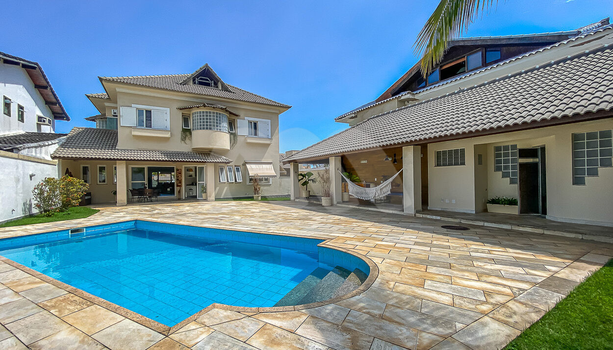Imagem frontal da piscina com vista da casa à venda em luxoso condomínio de mansões.