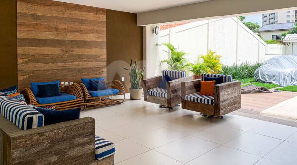 Imagem de varanda integrada a area gurme com sofá e poltronas em Caza a venda