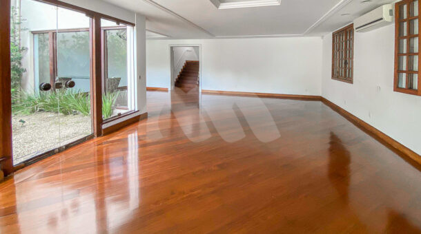 Imagem da ampla sala com piso de madeira da casa triplex no Pedra de Itaúna à venda na Barra da Tijuca