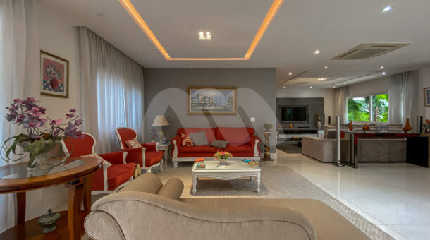 Imagem de sala de estar com sofás e poltronas em casa triplex a venda na Barra da Tijuca