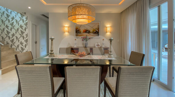 Imagem de sala de jantar com mesa e lustre em casa triplex a venda na Barra