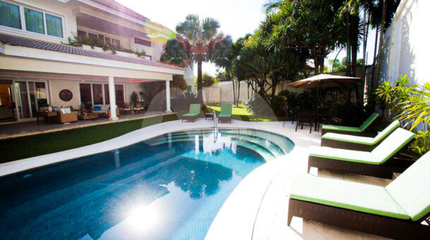 imagem da área externa com piscina e quintal gramado da casa triplex com elevador no condomínio Mandala
