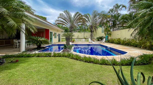 Imagem frontal da piscina com vista do paisagismo da linda casa à venda.