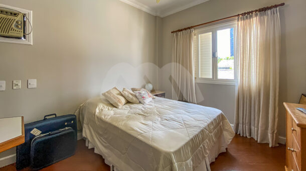 Imagem lateral do quarto com vista da cama de casal e janela da casa à venda em prestigioso condomínio.
