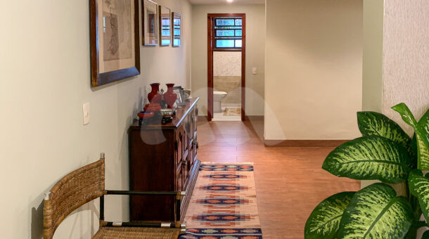 Imagem de corredor com aparador de madeira, cadeira e quadros em casa duplex a venda na barra