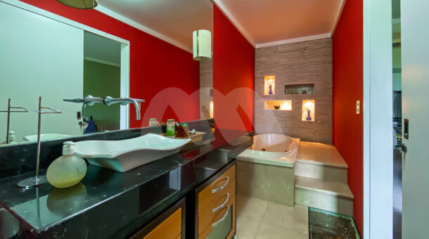 Imagem frontal do banheiro com detalhes em vermelho do imóvel à venda na imobiliaria Muller Imóveis RJ.