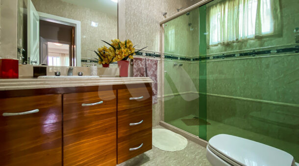 Imagem frontal do banheiro com vista da pia e box da casa à venda em prestigioso condomínio.
