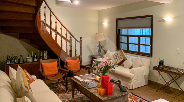 Imagem de sala de estar com escada em madeira para segundo andar e moveis de qualidade retro