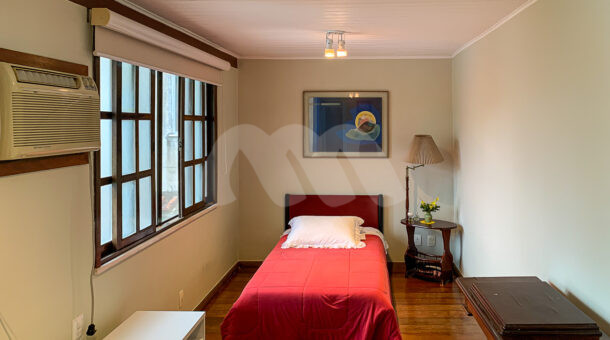 Imagem de quarto com cama de solteiro, quadro e mesa de cabeceira em casa duplex a venda na barra da tijuca