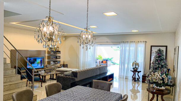 Imagem de sala ampla com mesa de jantar e dois lustres em casa triplex moderna na Barra da Tijuca