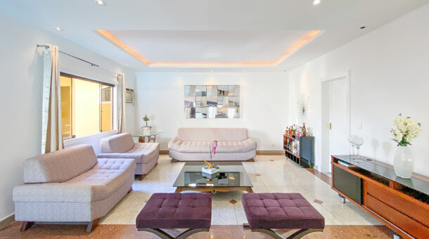 Imagem frontal da sala com vista dos sofás da mansão moderna à venda na Muller Imóveis RJ.