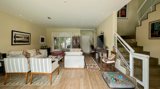 Imagem da sala com sofás e escada da casa à venda na Muller Imóveis RJ no Recreio