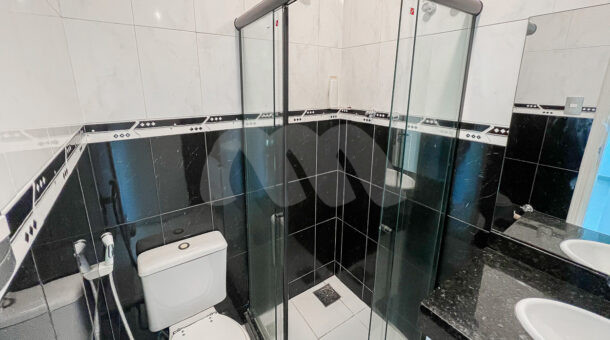 Imagem lateral do banheiro com detalhes em preto e branco do imóvel à venda em condomínio de mansões.