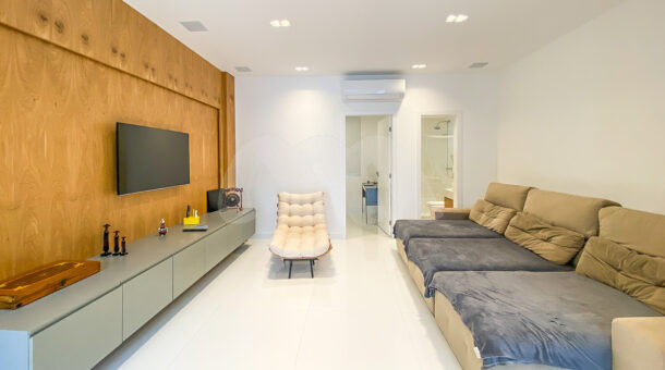 Imagem da sala com tv e amplo sofá da casa à venda no Recreio dos Bandeirantes. Imobiliária de luxo RJ