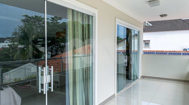 Imagem de varanda com portas de correr em blindex para acesso aos quartos da casa triplex à venda no Rio Mar