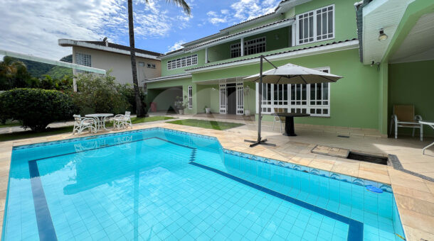 Imagem de area externa com piscina e ombrelone em casa a venda em regiao privilegiada da Barra