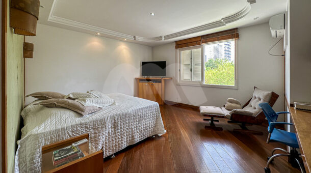Imagem de quarto com cama de casal, arandelas e long chair em casa duplex a venda