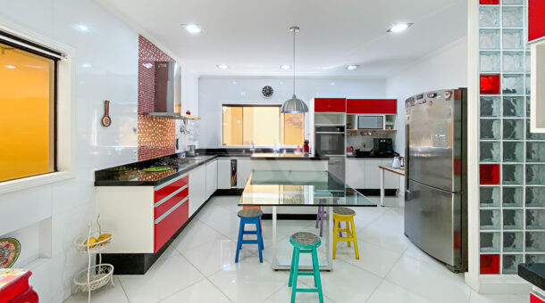 Imagem frontal da cozinha com vista da mesa central da casa à venda na Barra da tijuca.