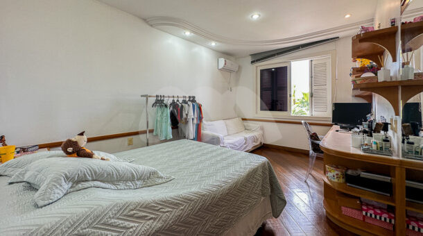 Imagem de quarto com cama de casal, penteadeira planejada e sofa da casa a venda na barra da tijuca
