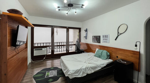 Imagem lateral do quarto com vista da cama de casal da linda casa à venda.