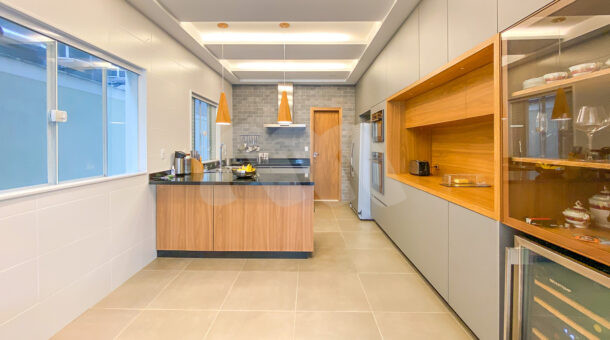 Imagem da ampla cozinha com grande bancada e armário planejados da casa à venda no Recreio dos Bandeirantes. Imobiliária de luxo RJ