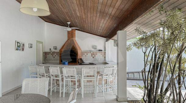 Imagem de area gourmet com churrasqueira, ilha com banquetas e ventilador de teto