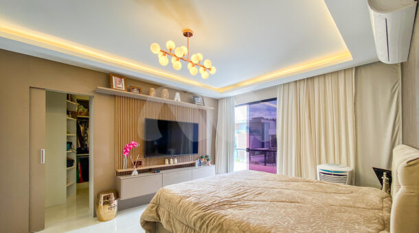 Imagem de suite com teto em gesso com iluminação, painel de tv e cama de casal em Casa Triplex à venda no Recreio