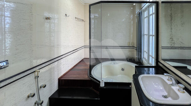 Imagem de banheiro de suite com banheira de hidromassagem em deck e bancada com cuba