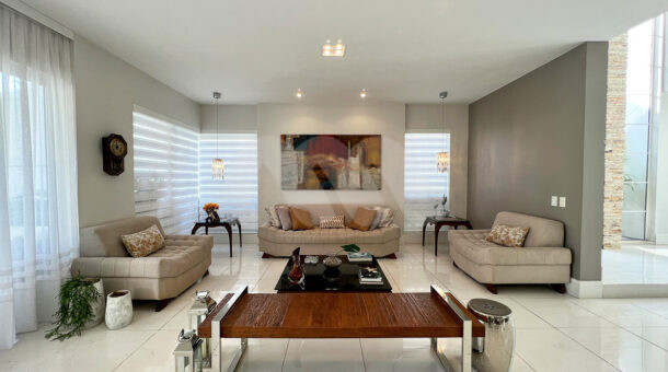 Imagem de hall com sofá e poltronas da casa duplex à venda no condomínio quintas do rio na barra da tijuca