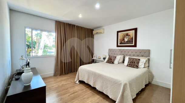 Imagem de quarto com cama de casal e cabeceira da casa duplex à venda no condomínio quintas do rio na barra da tijuca