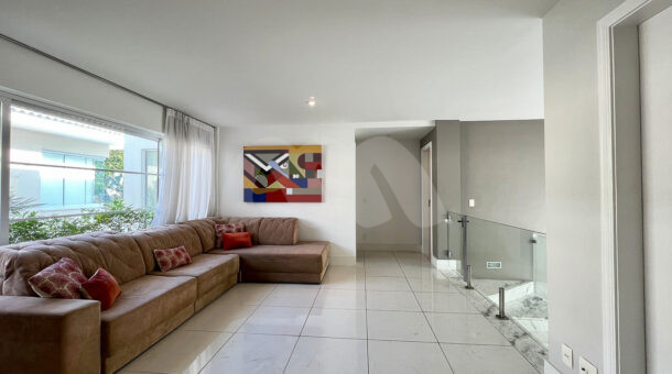 Imagem de sala intima com sofá em L da casa duplex à venda no condomínio quintas do rio na barra da tijuca