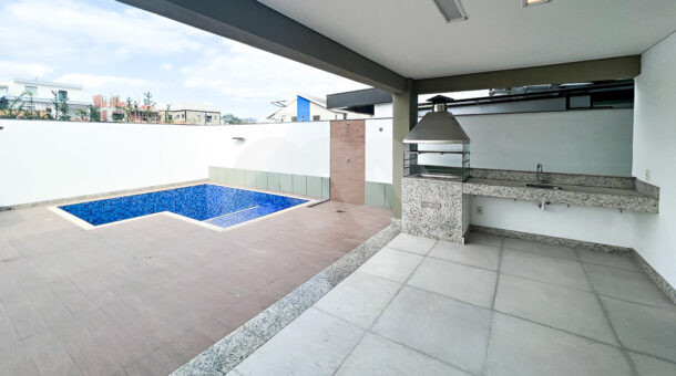 Imagem da área gourmet junto com a piscina da casa à venda em luxoso condomínio de mansões.