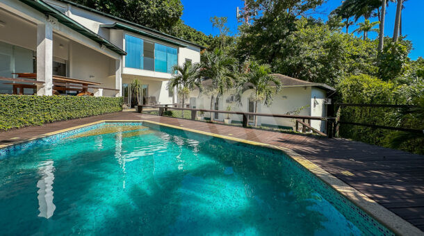 imagem da ampla piscina com deck de madeira e paisagismo da casa duplex no Portinho de Massaru à venda no Itanhangá