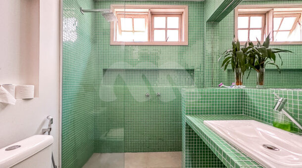 Imagem do banheiro com detalhes em verde do imóvel de luxo à venda.