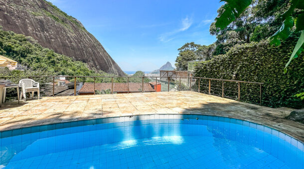 Imagem frontal piscina com vista da paisagem da mansão moderna à venda na Muller Imóveis RJ.